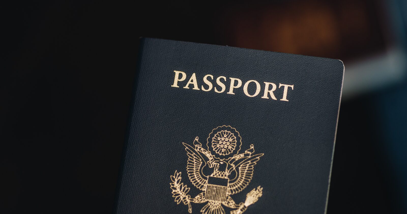 A United States passport, navy with gold lettering, on a dark background